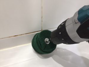 Drill-mounted abrasive cleaning discs removing grime from metal